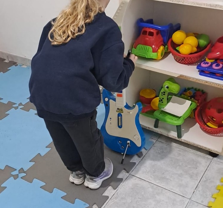 Niña explorando una guitarra en una sesión de musicoterapia en Kalebu CET