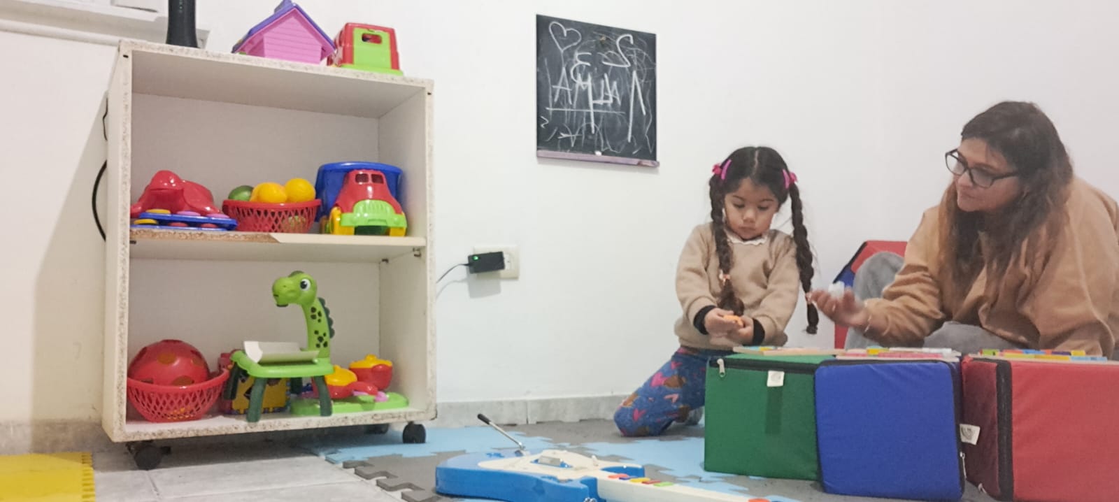 Sesión de psicomotricidad en Kalebu CET, profesional jugando en el piso con una niña